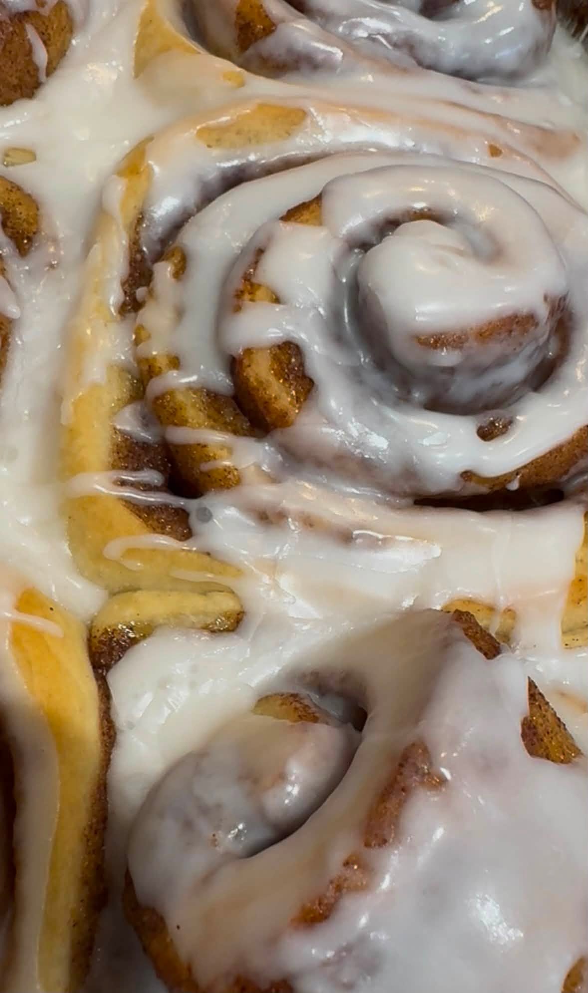 Freshly iced cinnamon buns in a tray